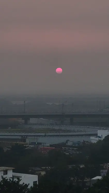 The Sun doesn't really "set". It just fades out as it descends behind the veil of smog.